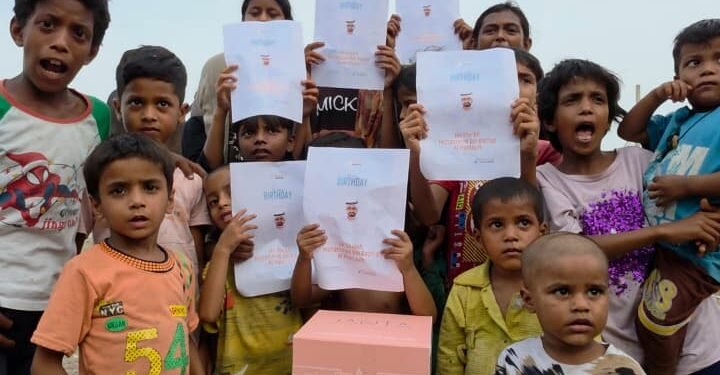 Underprivileged children in Delhi holding a birthday banner for His Highness Sheikh Mohammed bin Rashid Al Maktoum during a food distribution drive.