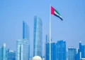 UAE flag waving in Abu Dhabi skyline under a clear sky.