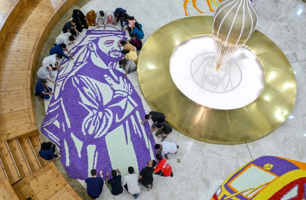 Healthcare workers at Burjeel Medical City standing around a 250-square-meter floral carpet featuring UAE President Sheikh Mohamed bin Zayed Al Nahyan.