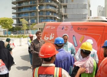 GDRFA officers distributing cold drinking water and refreshments to outdoor workers in Dubai during summer.