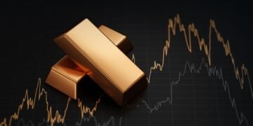 Stack of gold bullion bars and financial market trading screen display