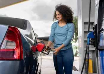 Petrol dispensing nozzle at an Emirates fuel station with digital fuel prices in the background