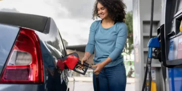 Petrol dispensing nozzle at an Emirates fuel station with digital fuel prices in the background