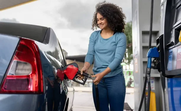 Petrol dispensing nozzle at an Emirates fuel station with digital fuel prices in the background
